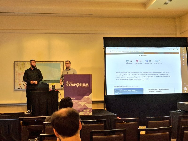 Adam Lamarre and Bryan Mills stand at a podium presenting at Sitecore Symposium.